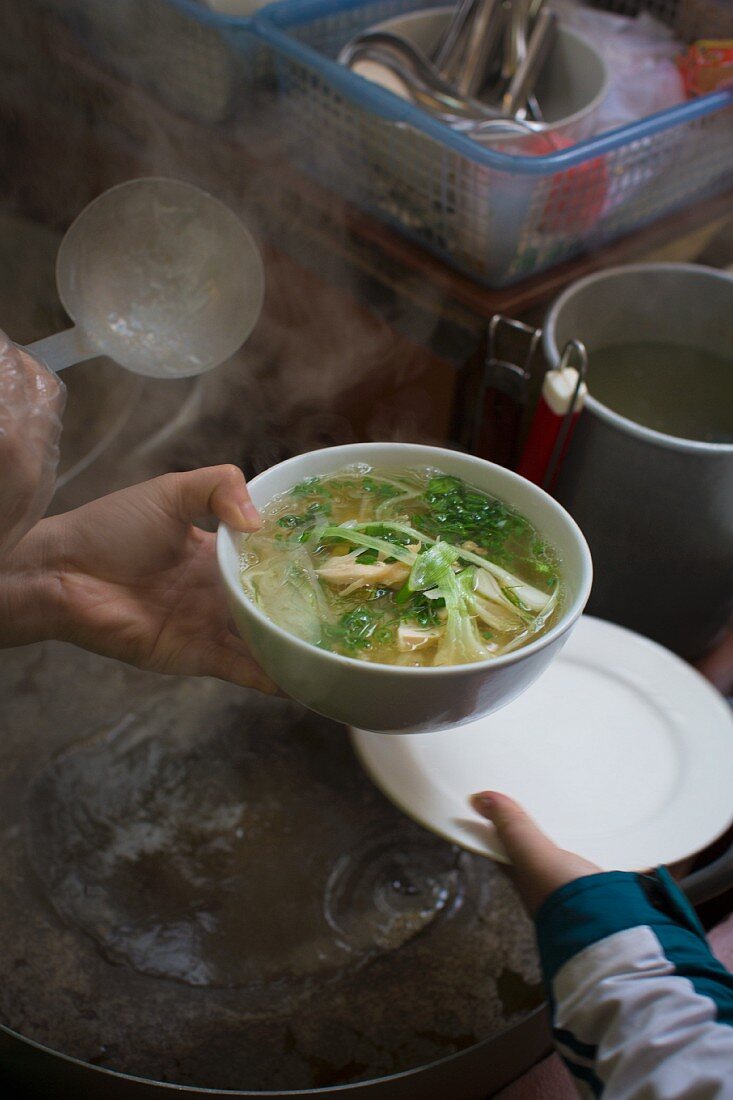 A steaming bowl of Vietnamese Pho soup in a street kitchen