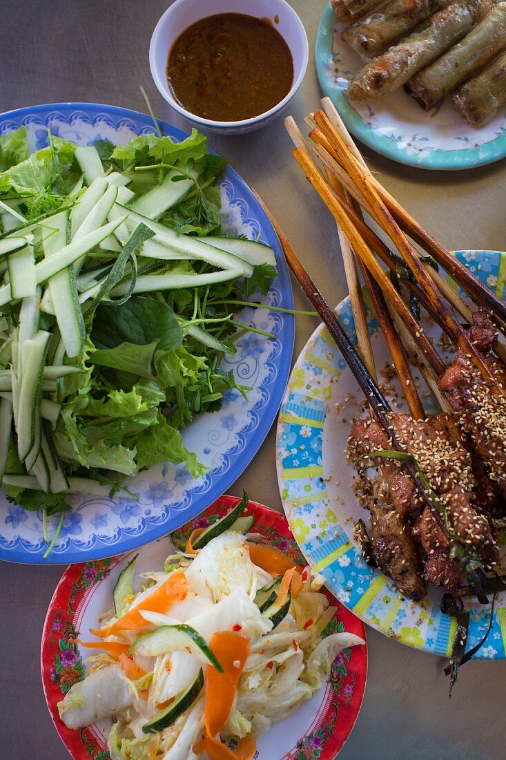Grilled pork skewers, spring rolls, herbs and cucumber (Vietnam)