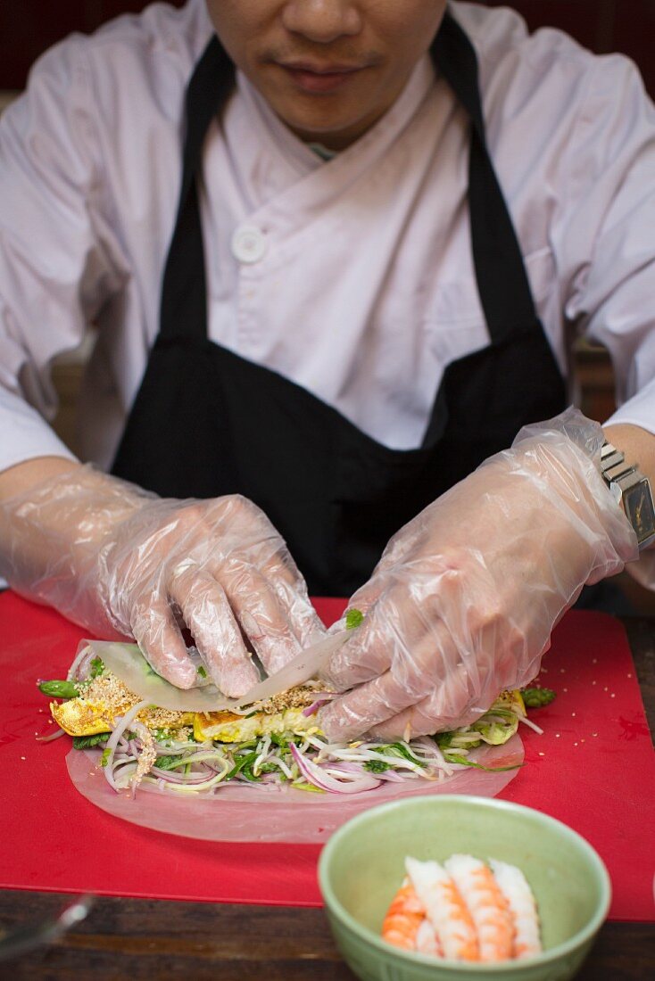 A chef preparing a Vietnamese spring roll with tofu