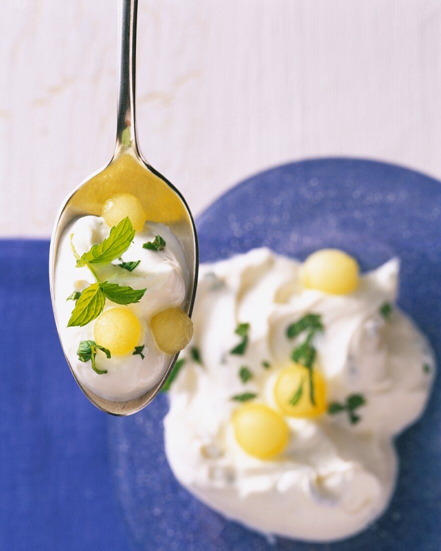 Ein Löffel Quarkcreme mit Trauben und Minze