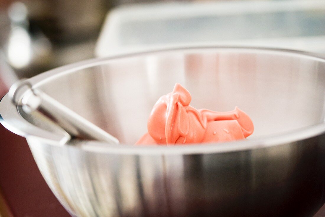 Pink meringue for making macaroons in a mixing bowl
