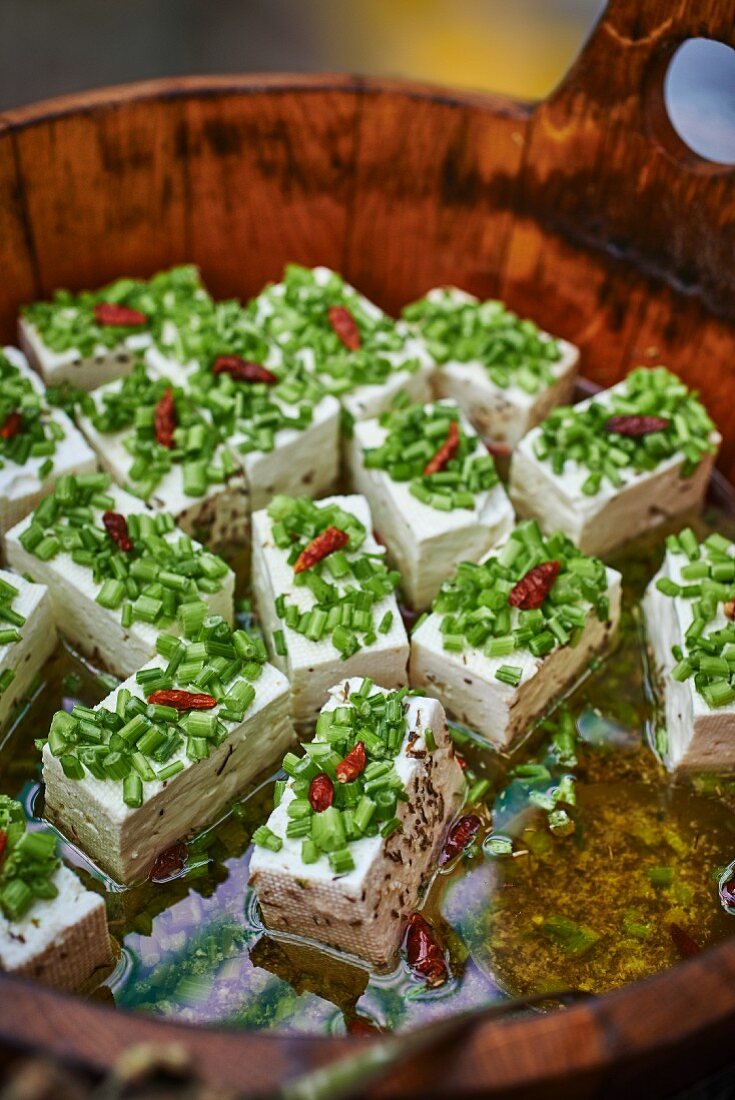 Marinated goat's cheese with olive oil and chives in a wooden barrel