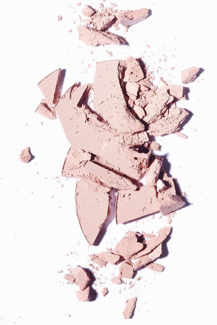 Crumbled compact powder on a white surface
