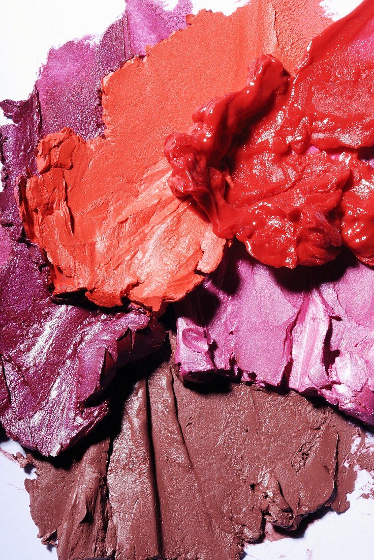 Lippenstifte in Rosé- und Rottönen verstrichen auf weißem Untergrund