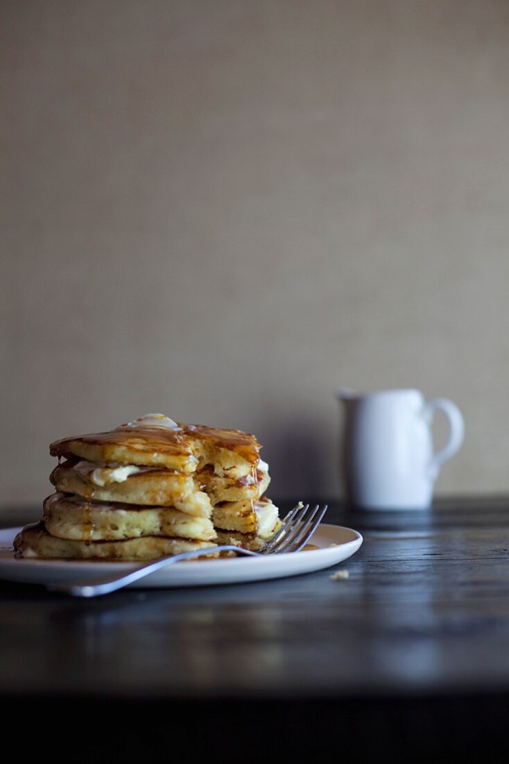 A stack of pancakes with maple syrup, sliced