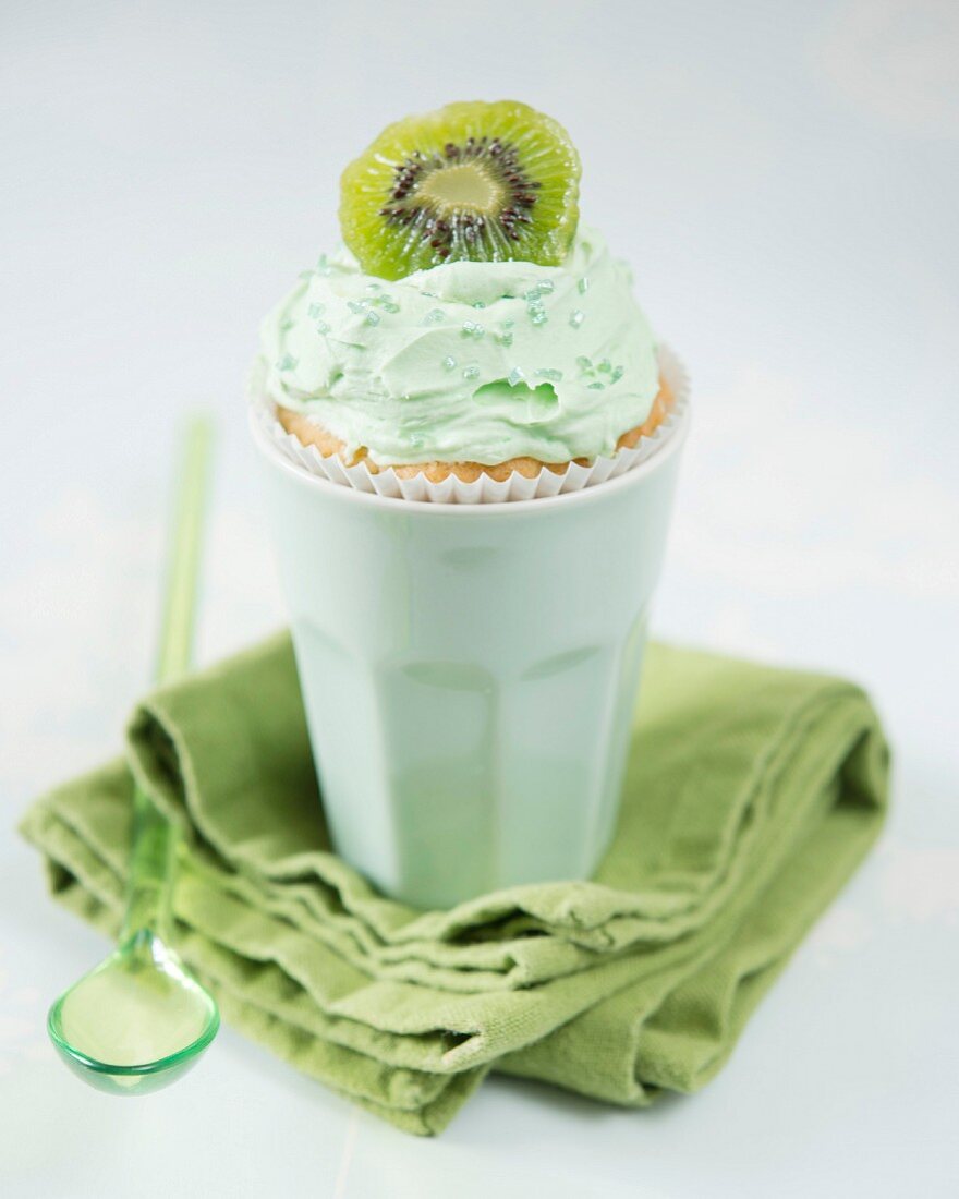 A kiwi cupcake in a ceramic cup