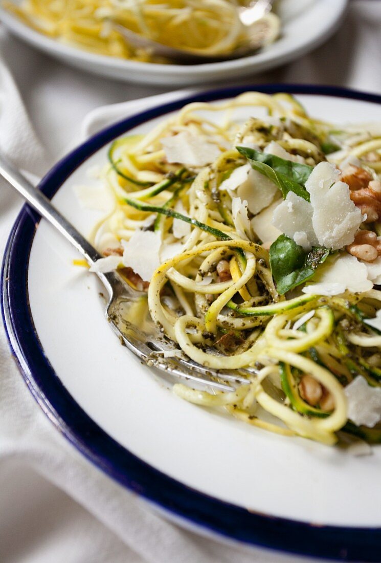Ein Teller 'Spaghetti' aus spiralisierten Zucchini mit Pesto, Walnüssen und Parmesan