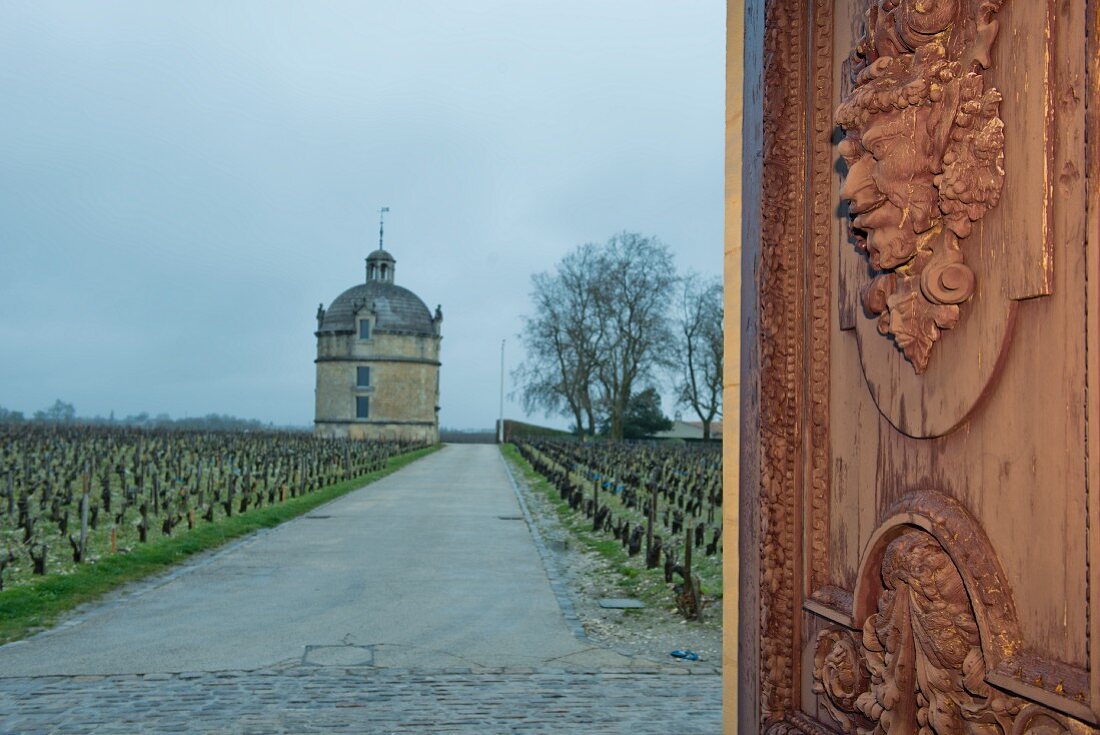 A view of a tower at the Chateau Latour vineyard through a wooden gate (Bordeaux, France)