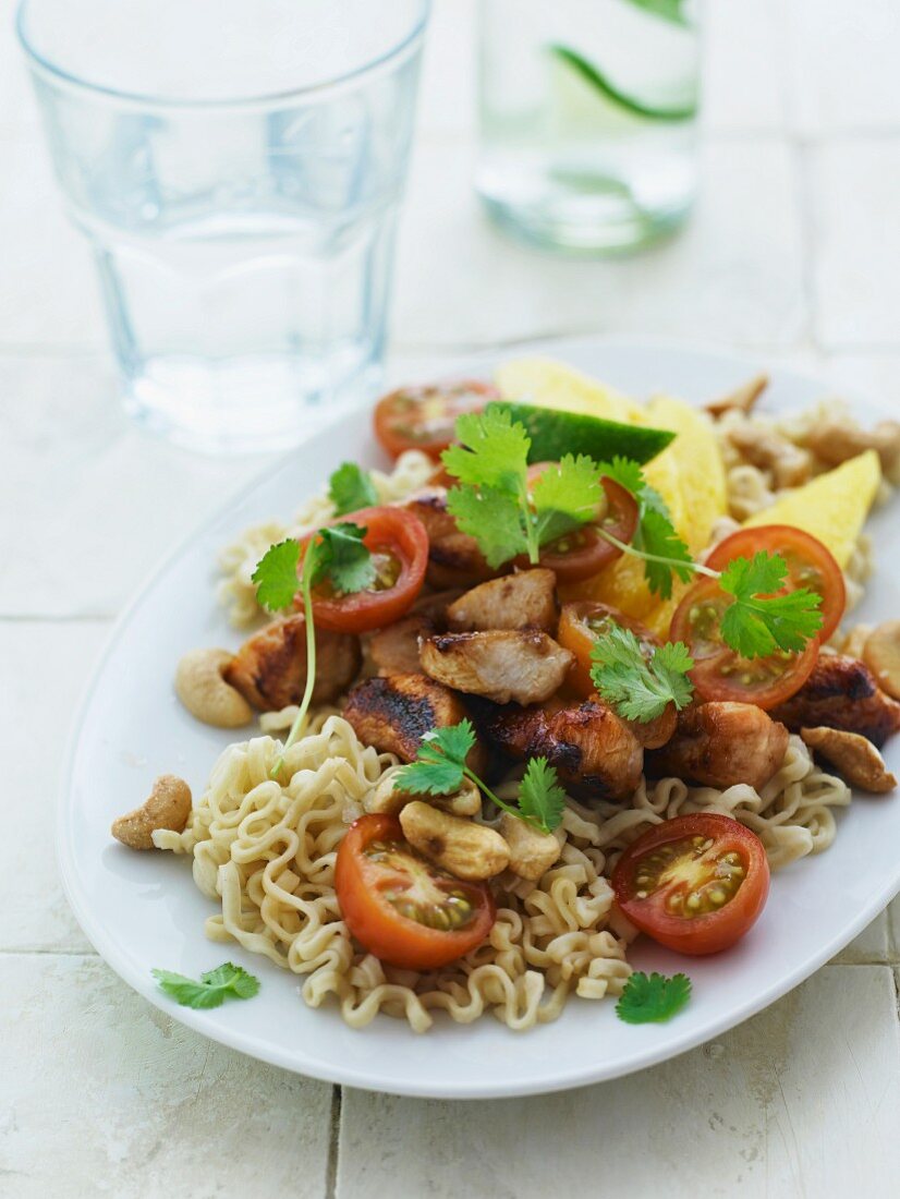 Noodles with marinated chicken, tomatoes, coriander, cashew nuts and lines
