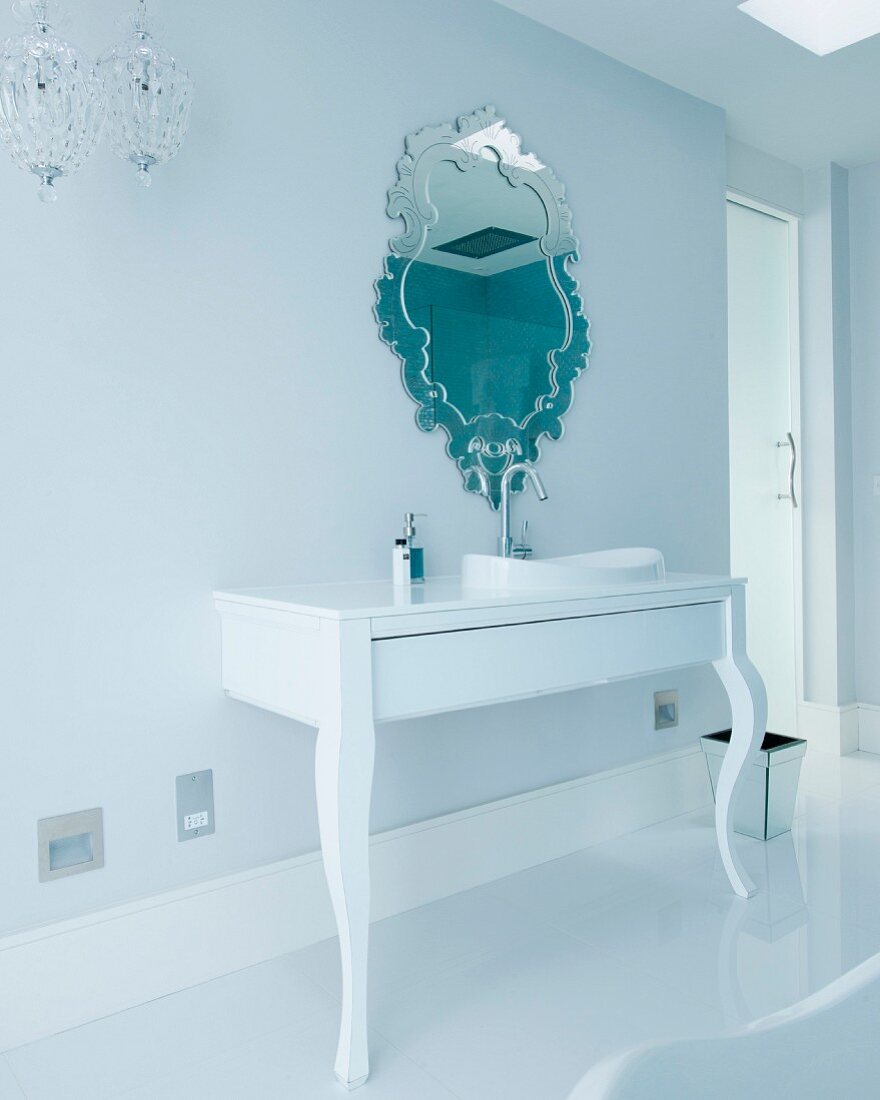 Elegantes Designerbad mit verziertem Wandspiegel über Waschbecken in postmodernem Konsolentisch