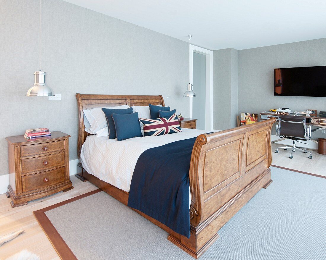 Spacious room with Union Flag scatter cushions on solid wooden bed and desk and swivel chair in background