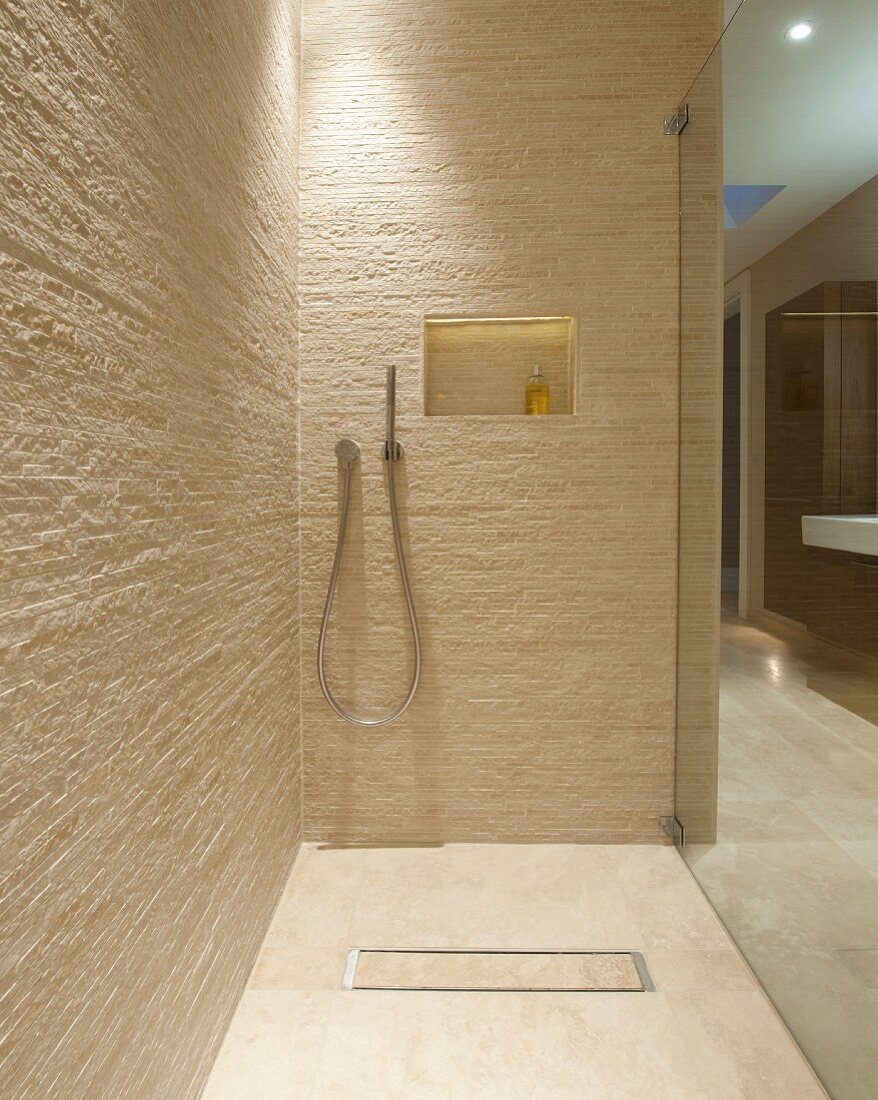 Begehbare Dusche in Designerbad mit Fliesen im Naturlook; Ablagenische mit indirekter Beleuchtung in der Rückwand