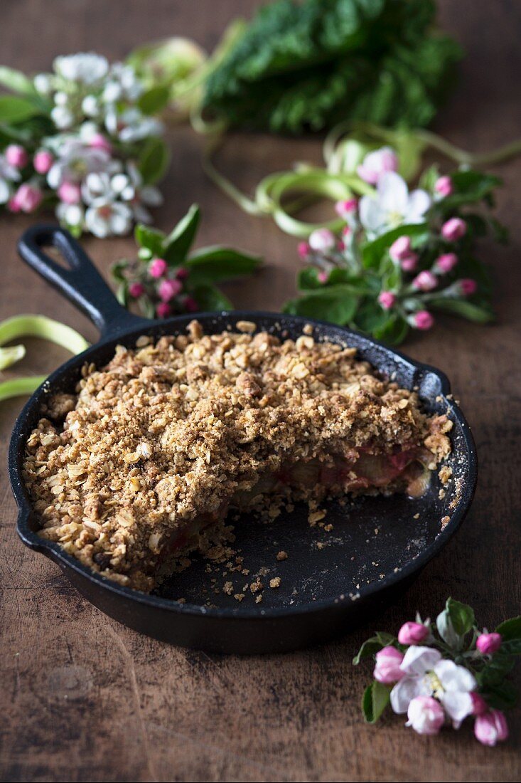 Rhabarberpie in der Pfanne auf Holzuntergrund mit Frühlingsblüten