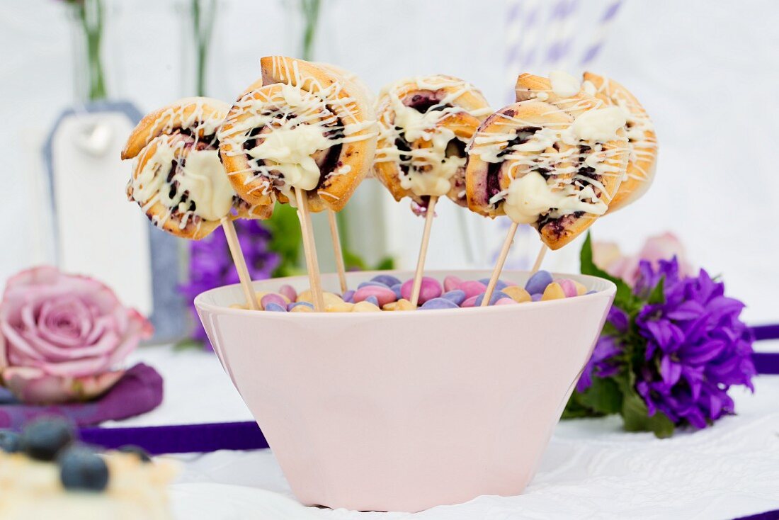 Mini blueberry pastries on sticks in a pink bowl