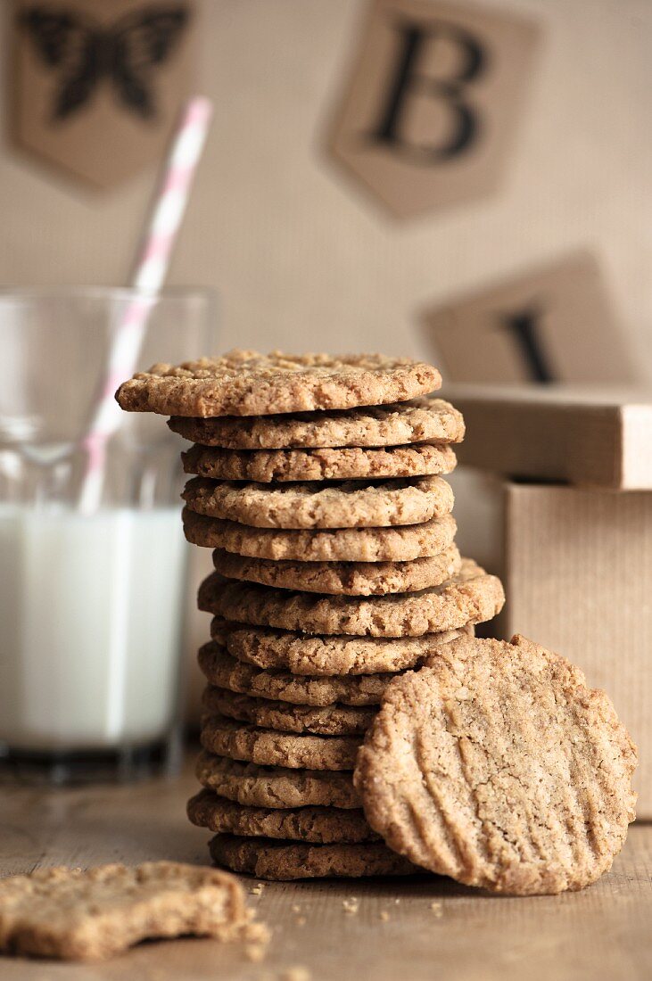 A stack of homemade oat biscuits with a glass of milk in the background