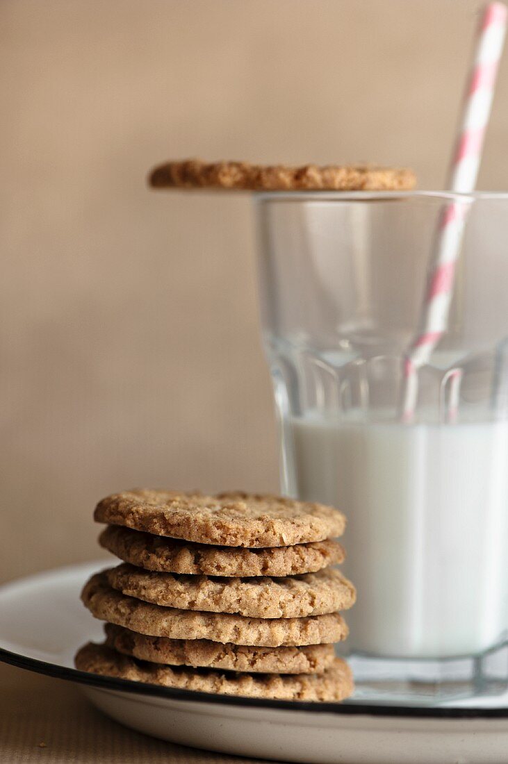 A stack of biscuits next to glass of milk