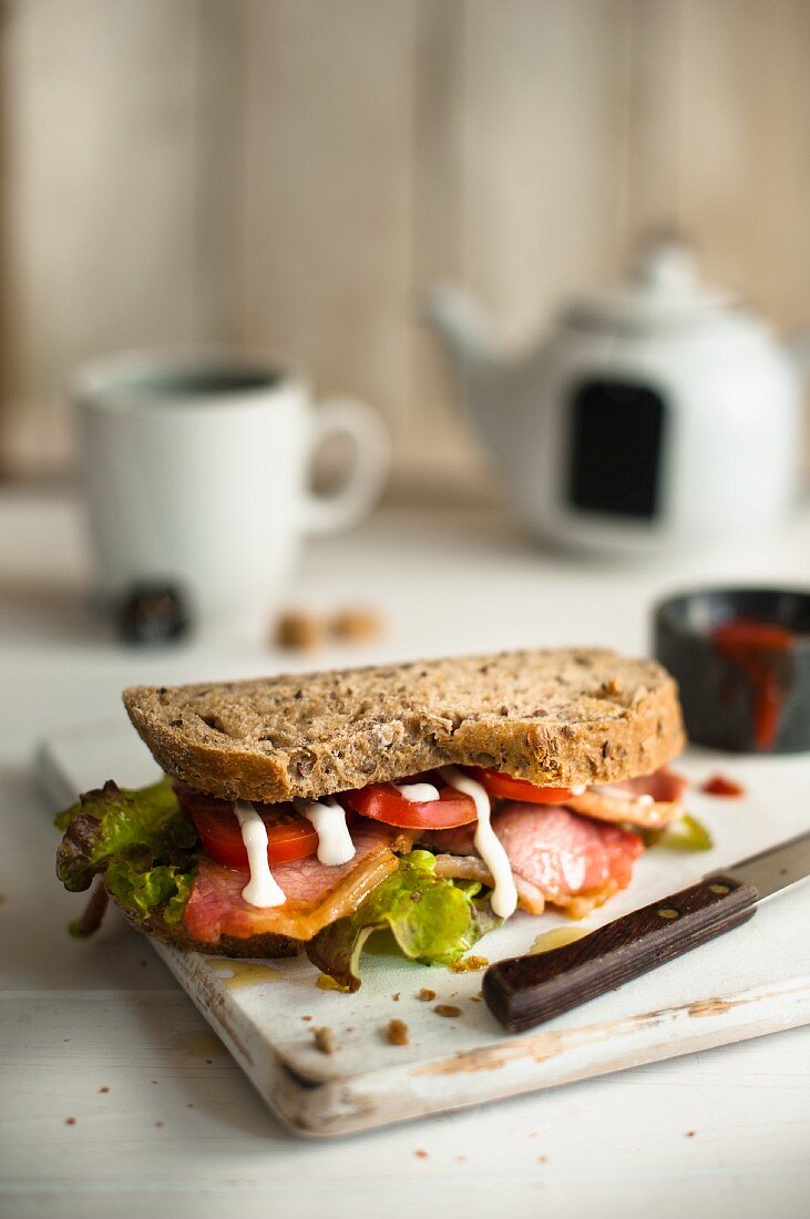 Bacon, lettuce and tomato sandwich with mayonnaise on a chopping board