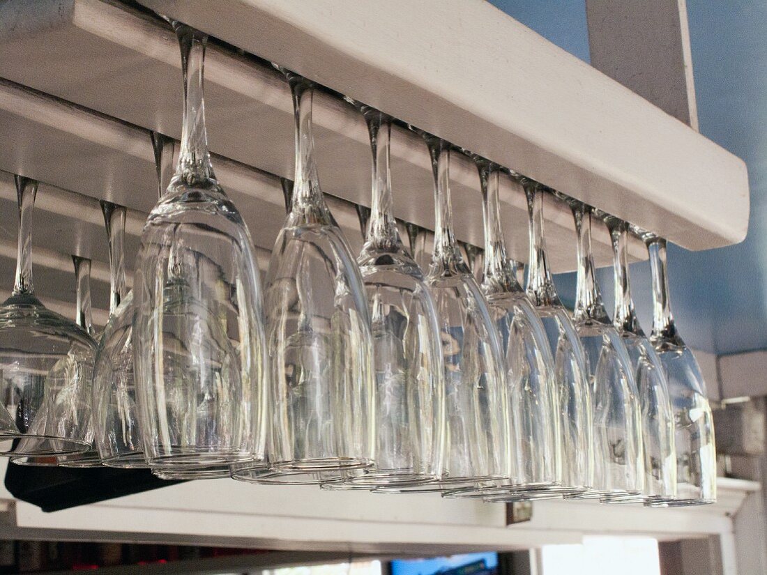 Champagne and wine glasses hanging upside down in a shelf in a restaurant