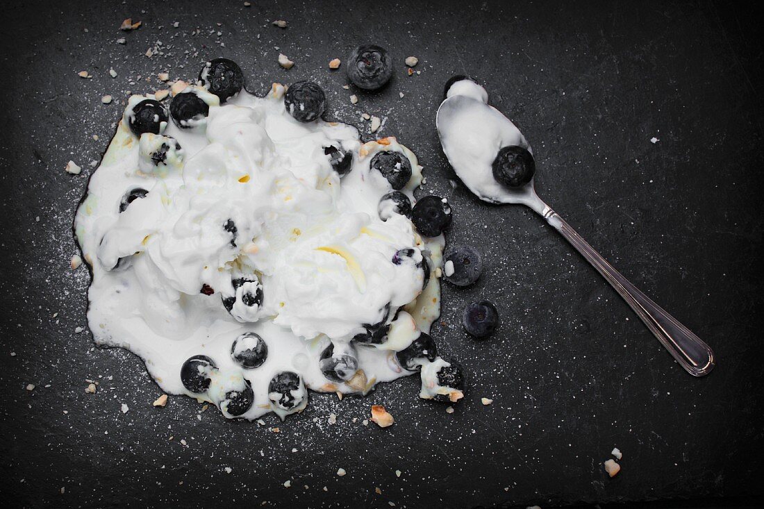 Melted yoghurt ice cream with blueberries and a teaspoon