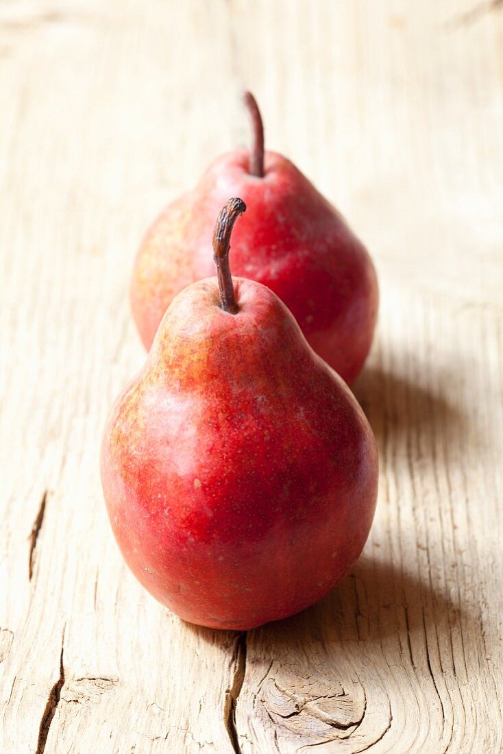 Two red pears on a wooden surface