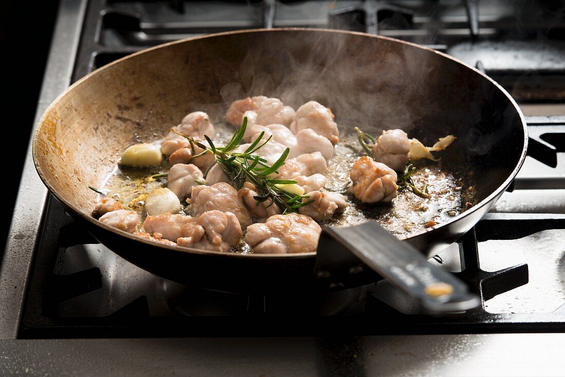 Fried veal sweetbreads with garlic and rosemary in a pan