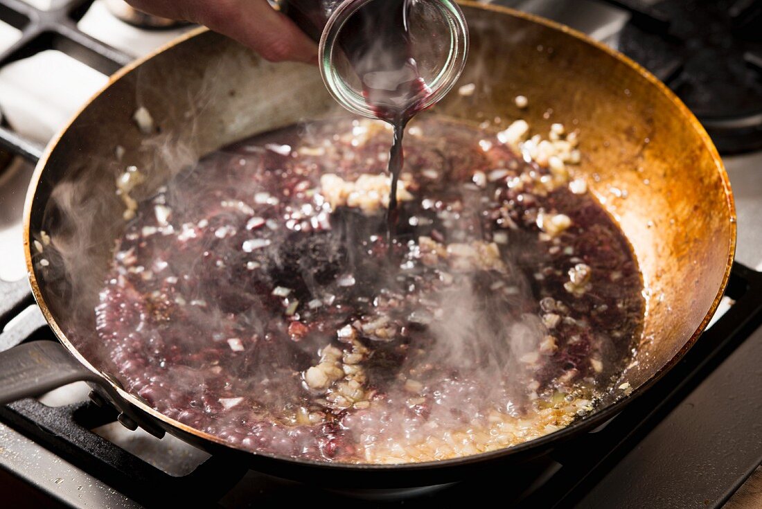 Red wine being added to a pan