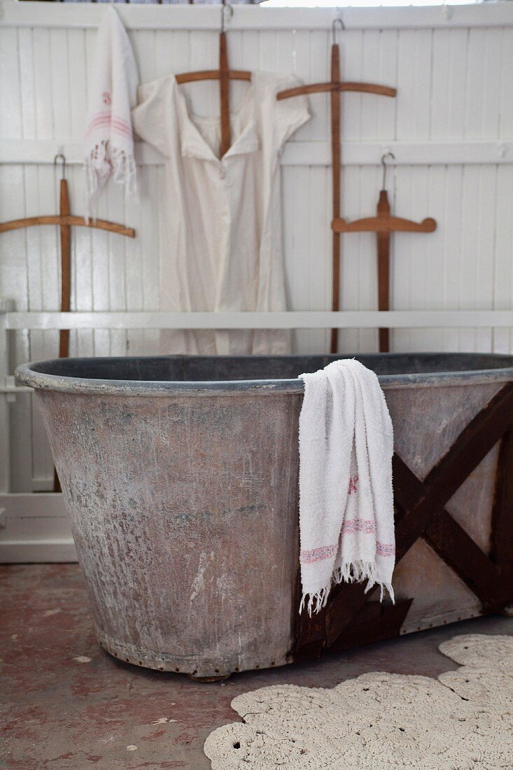 Old zinc bathtub and crocheted bathmat in vintage-style bathroom