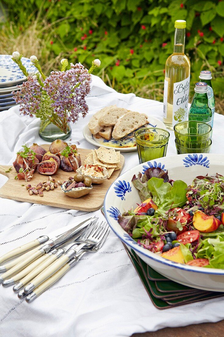 Sommerlicher Buffettisch im Freien mit Salat, Häppchen und Getränken