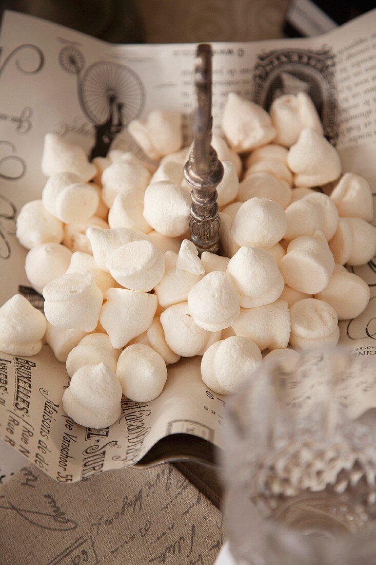 White meringues on vintage-style paper on cake stand