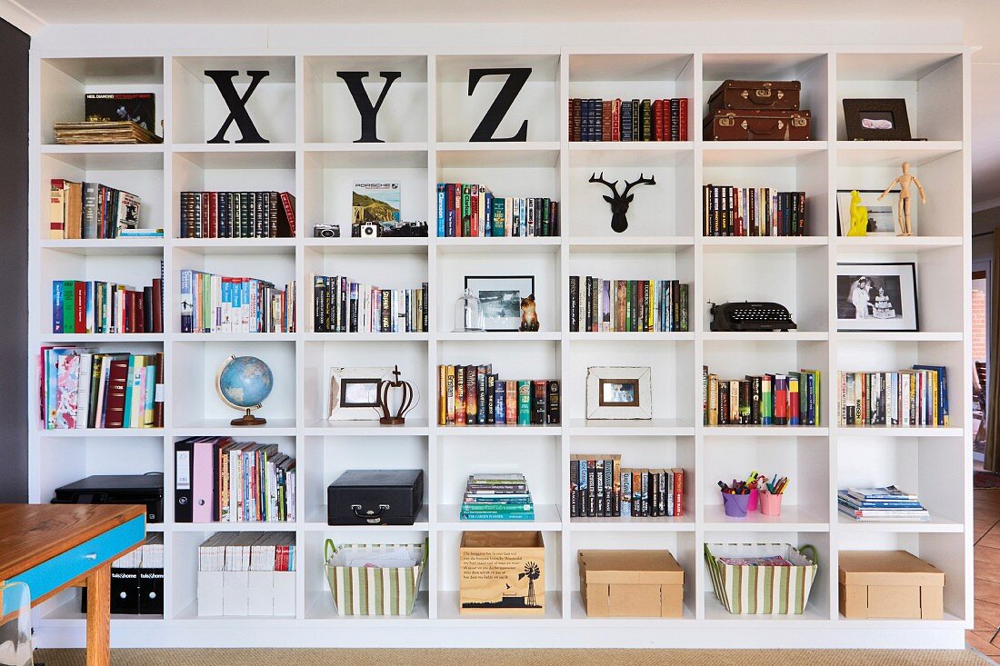 Books and storage baskets on white, floor-to-ceiling shelving