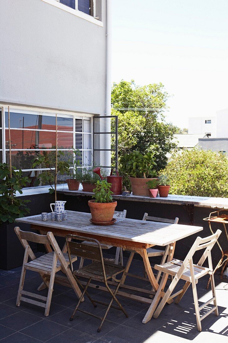 Terrasse eines mehrstöckigen Wohnhauses mit schlichtem Holztisch und Stühlen