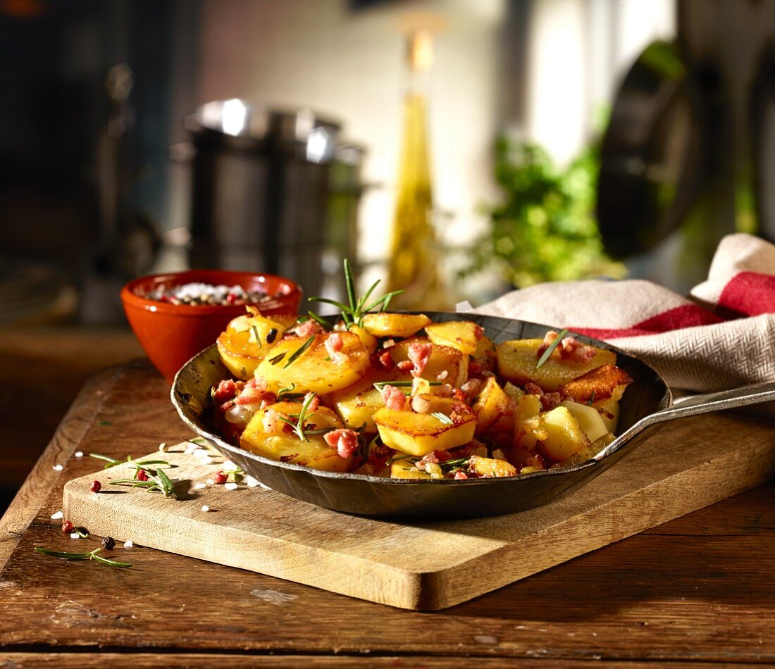 Fried potatoes with bacon and rosemary in a rustic pan