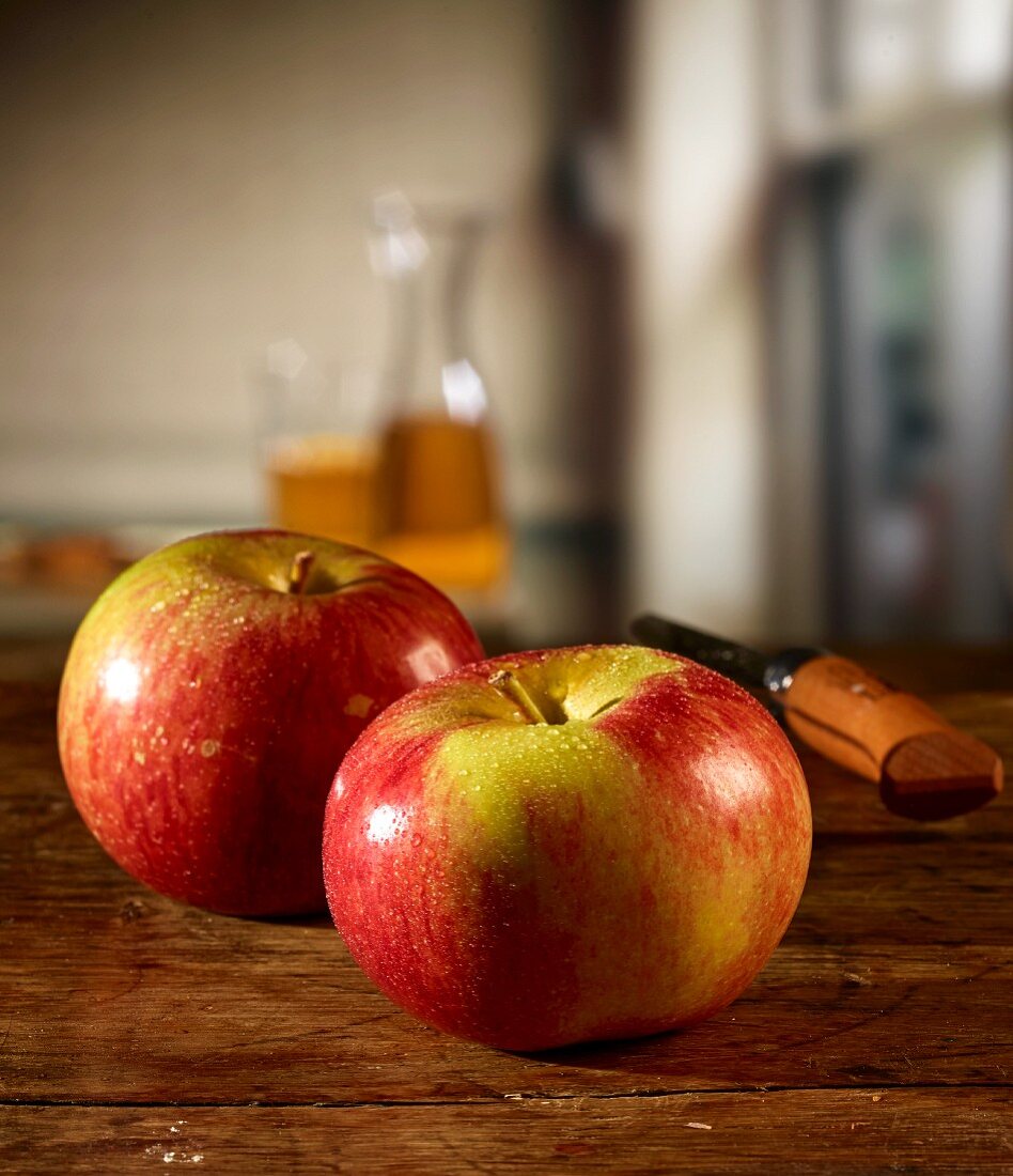 Rote Äpfel auf Holztisch und Apfelsaft im Hintergrund