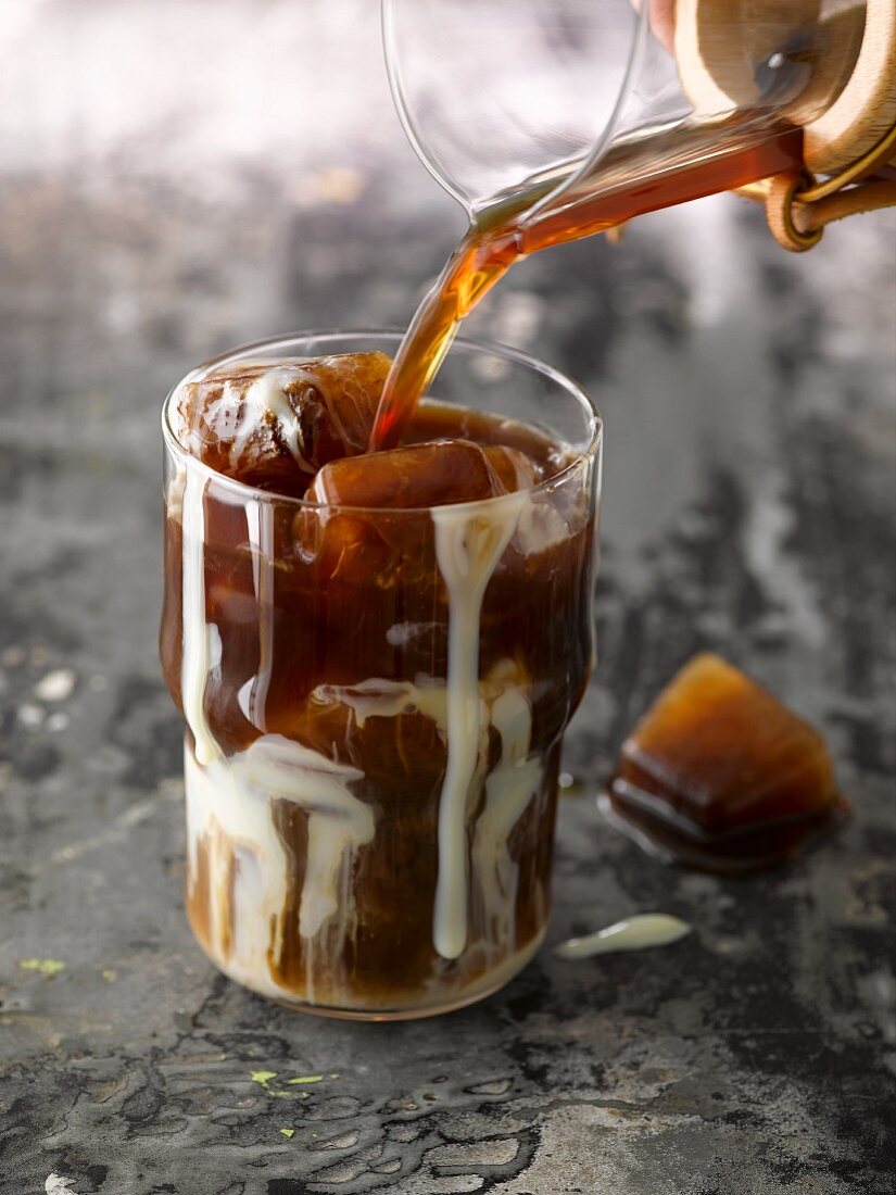 Iced coffee being made: coffee being poured over coffee ice cubes