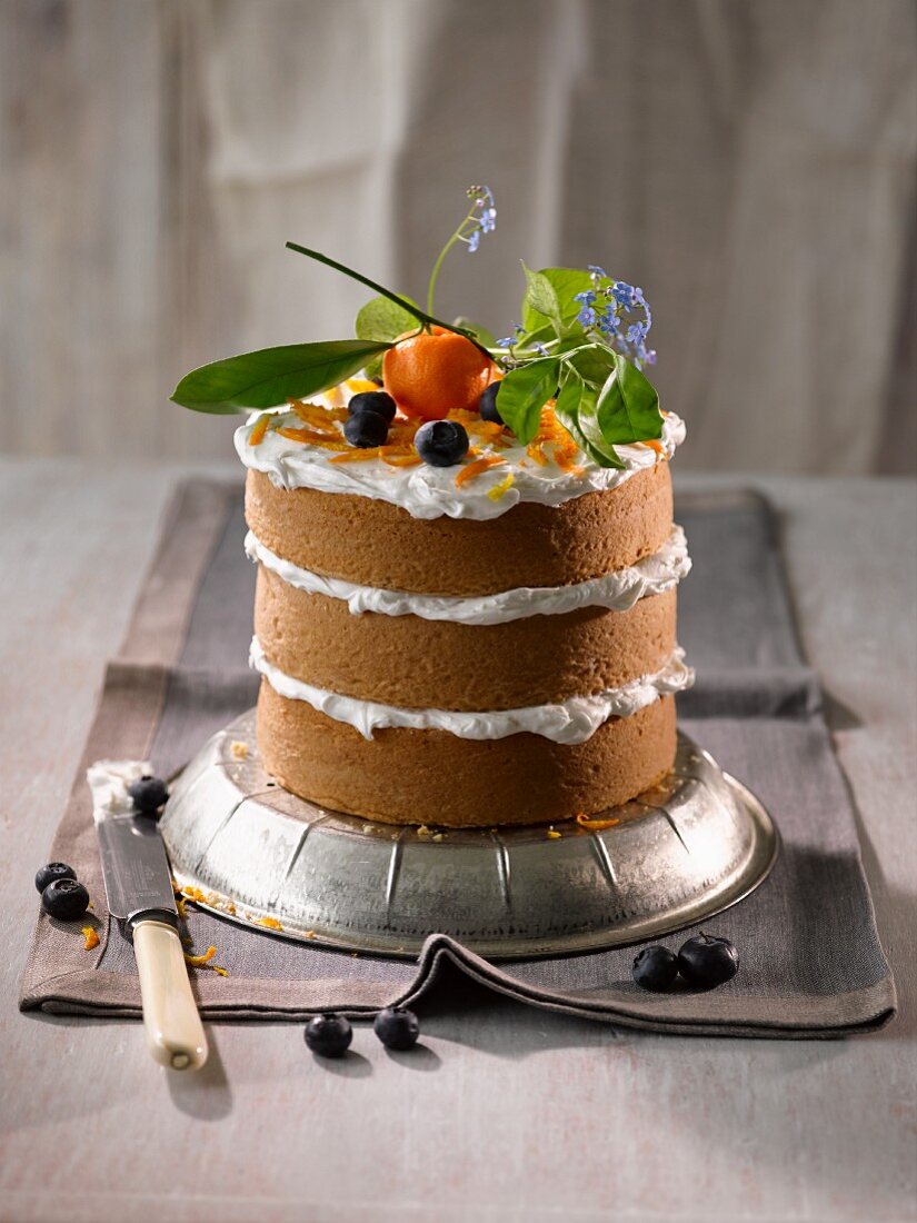 A triple layer mini cake with a cream filling garnished with ornamental oranges