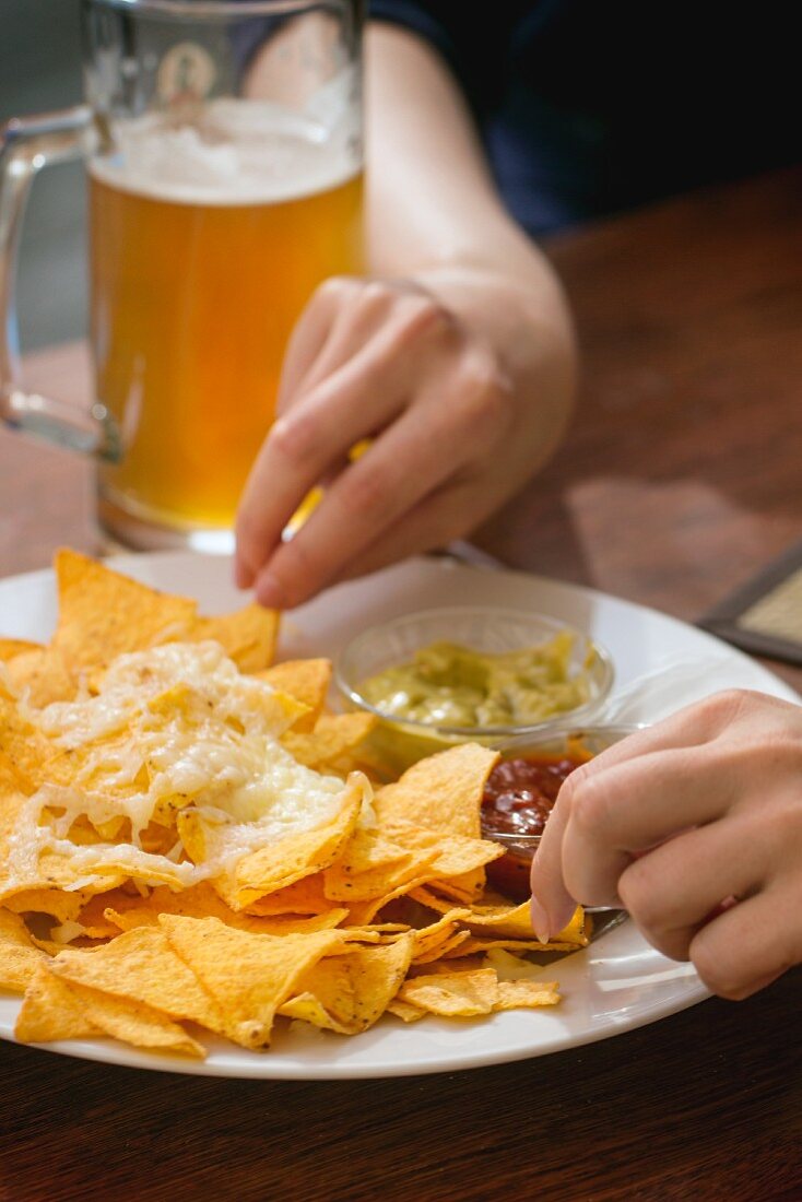 People eating nachos with cheese and two dips