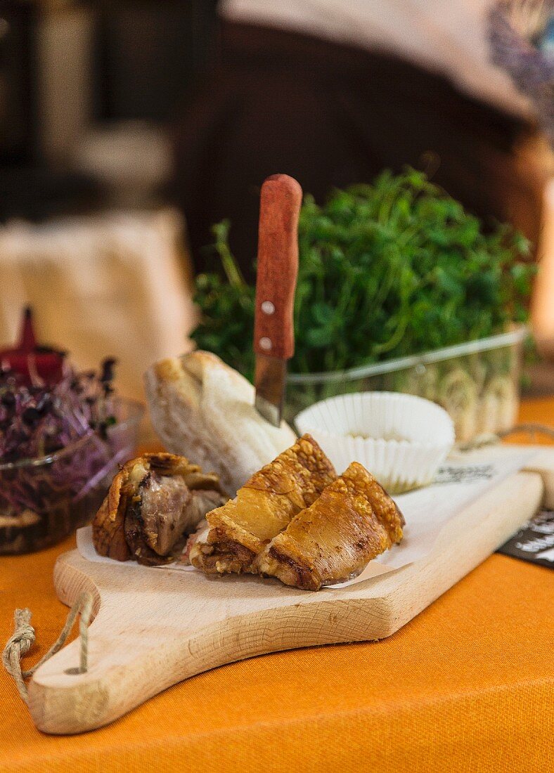 Schweinshaxe und Brötchen auf Schneidebrett