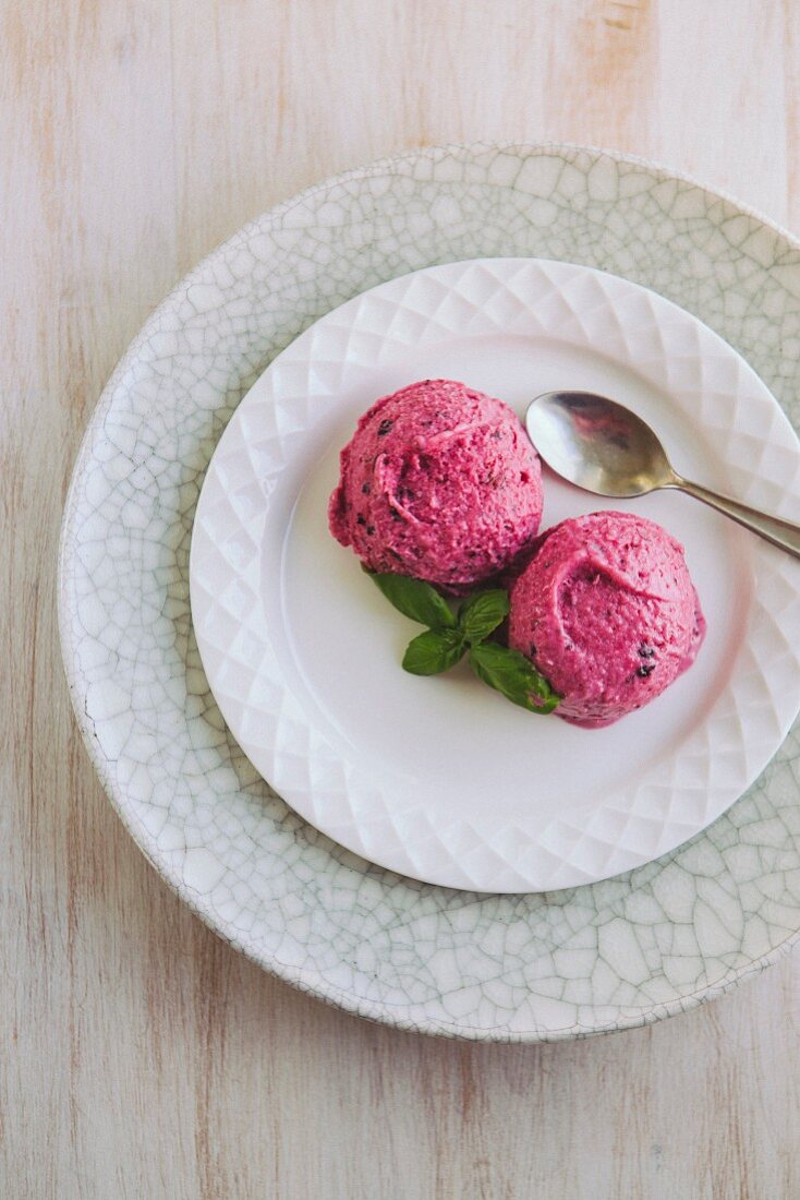 Two scoops of banana and berry ice cream on a plate with a spoon