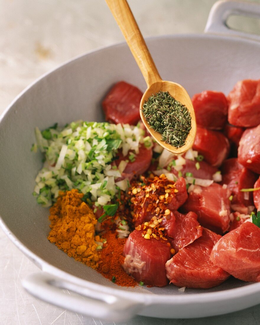 Diced meat being mixed with herbs, spices and onions