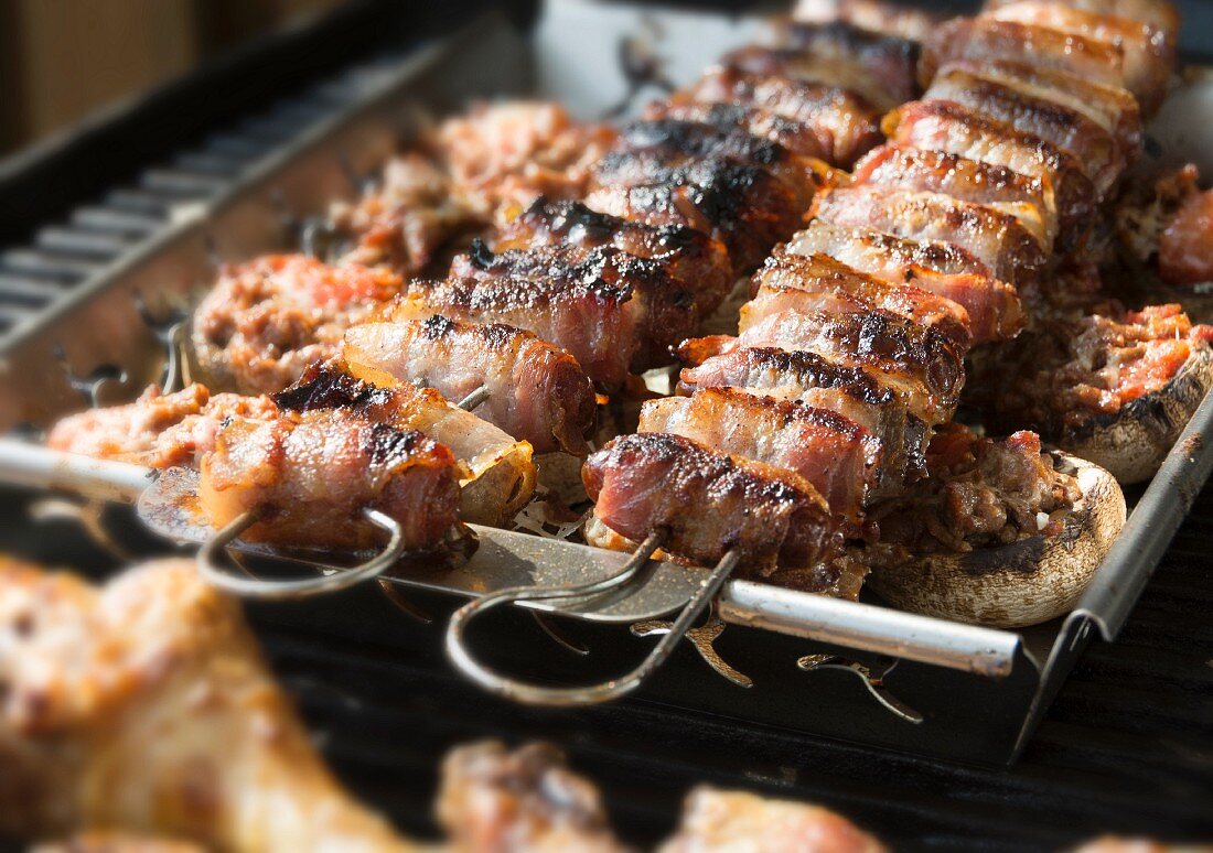 Stuffed mushrooms and figs wrapped in bacon on a grill