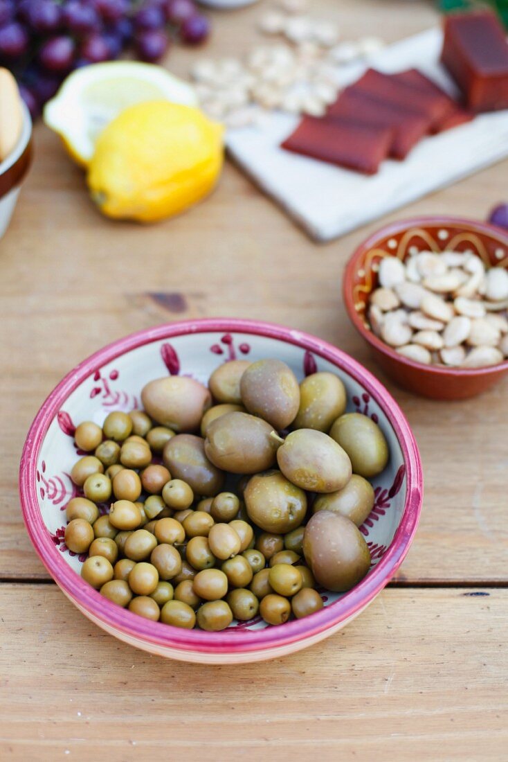Two types of green olives in a ceramic bowl