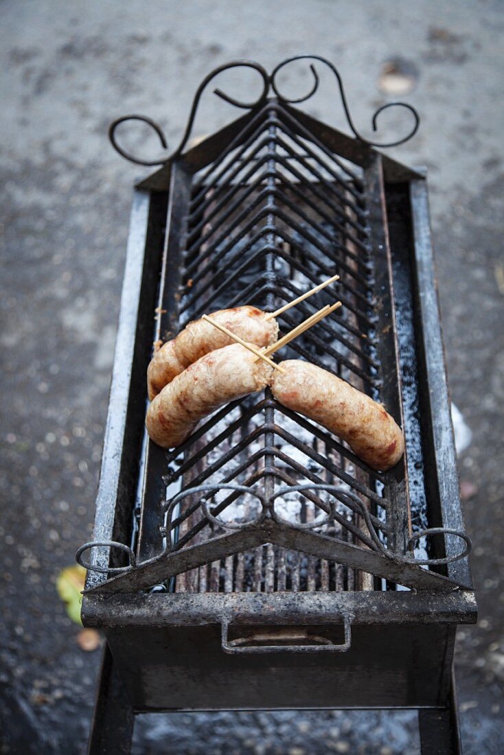 Sausages on wooden sticks on a barbecue