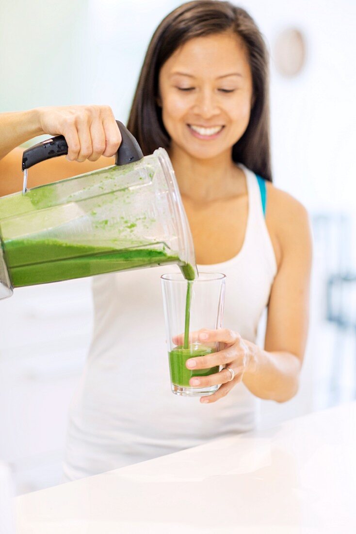 A woman pouring a smoothie into a glass