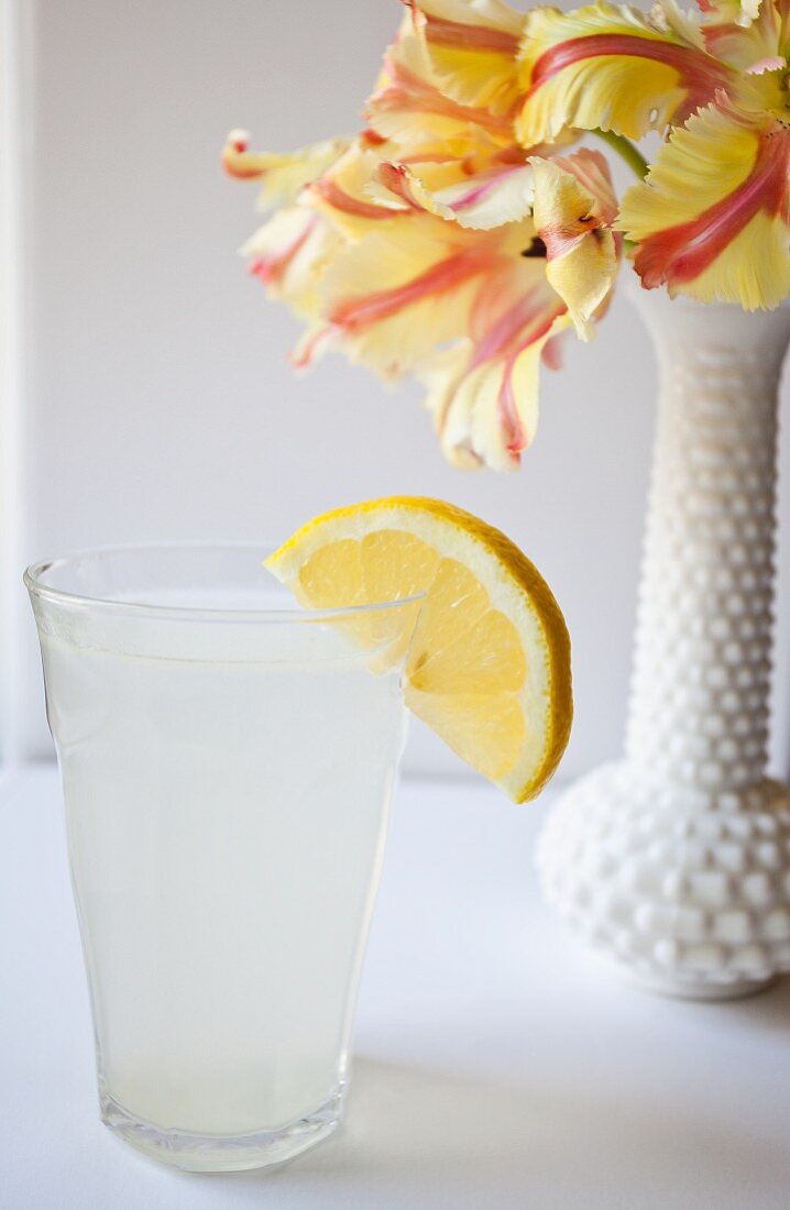 Ein Glas Zitronenwasser neben Blumenvase