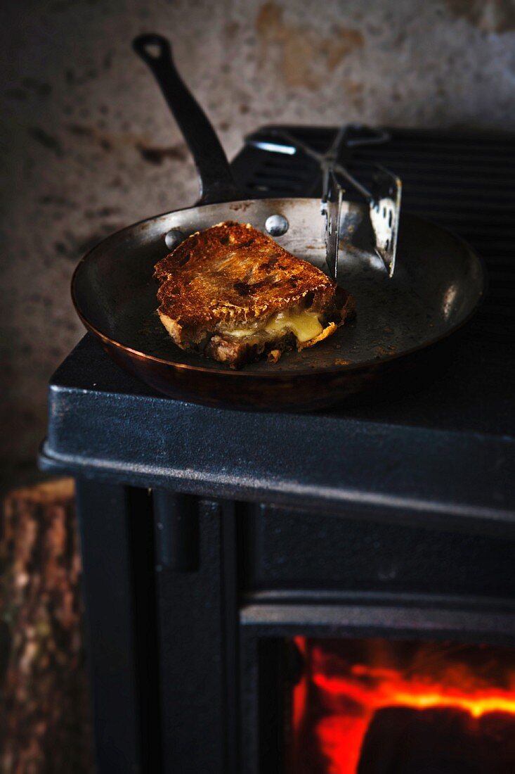 A grilled cheese sandwich in a pan over a stove