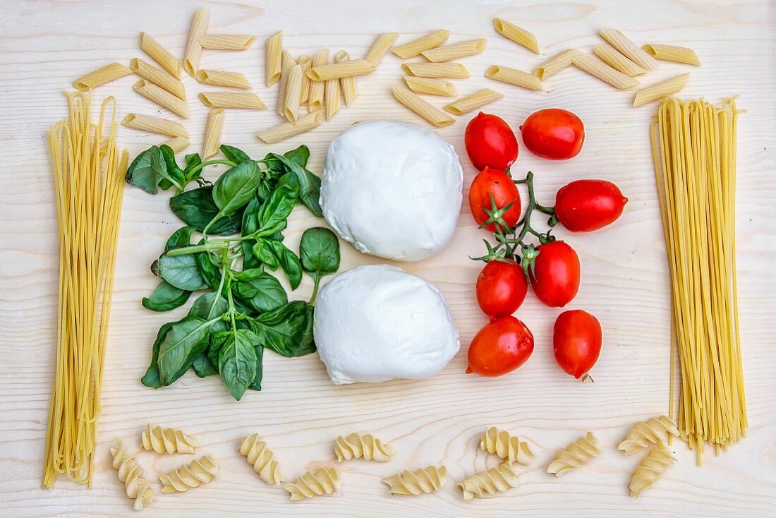 An arrangement of Italian food (pasta, basil, mozzarella and tomatoes)