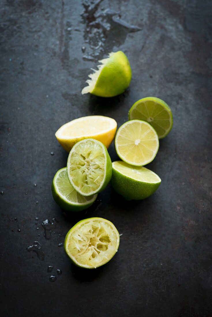 Lime halves, some juiced, on a black surface