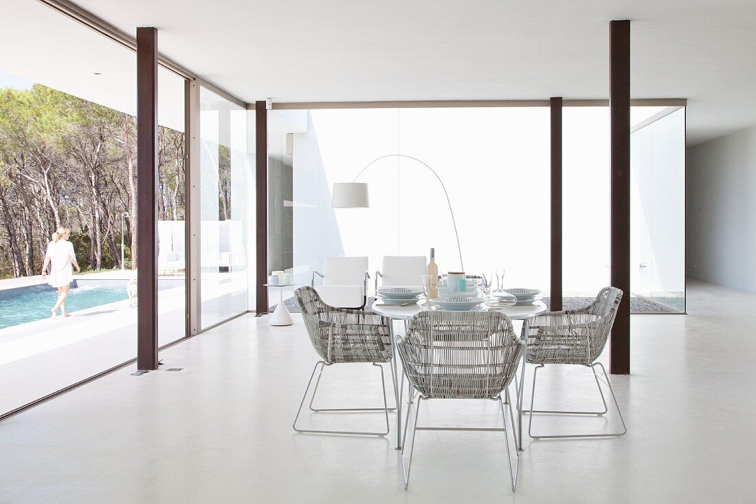 Dining area in minimalist luxury interior with steel pillars and view of pool