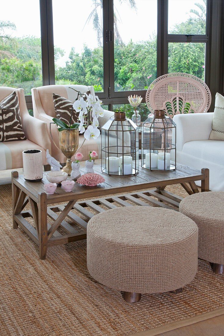 Pouffes at coffee table with candle lanterns and vases of flowers in conservatory