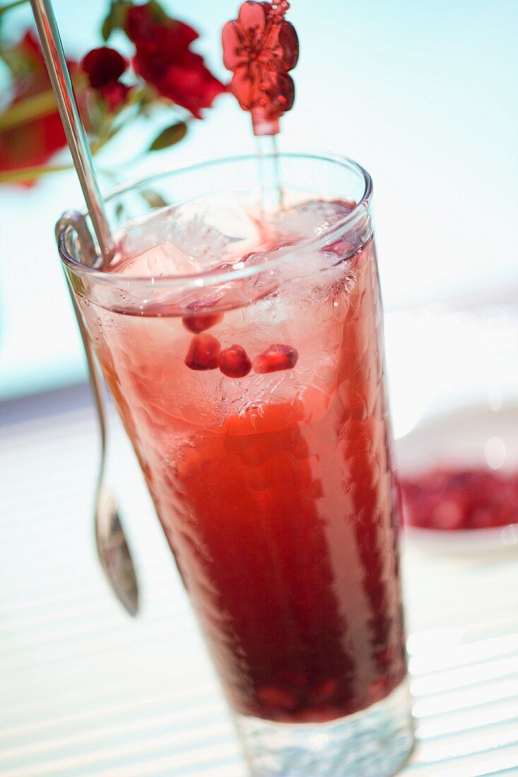 A glass of pomegranate drink with ice cubes